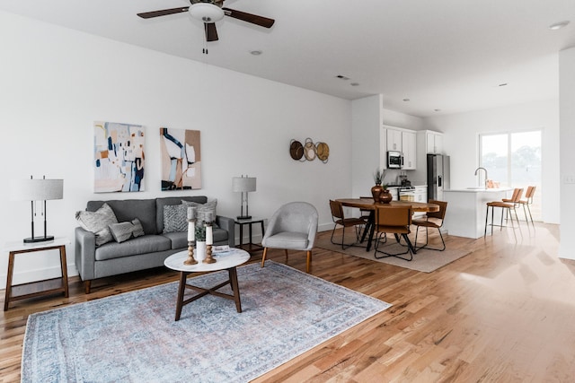 living room with ceiling fan, sink, and light hardwood / wood-style floors