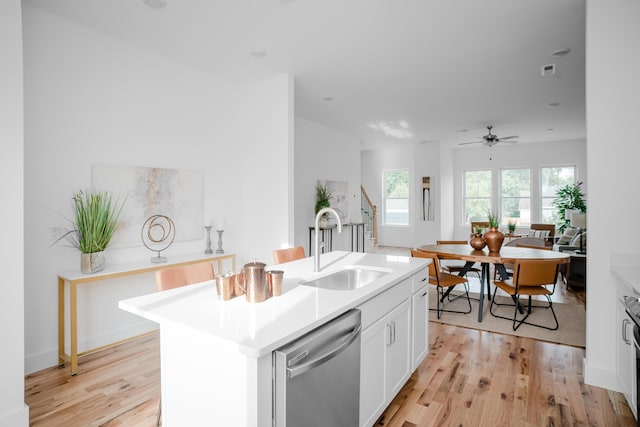 kitchen with ceiling fan, light wood-type flooring, an island with sink, and dishwasher