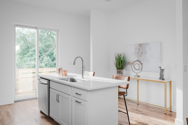 kitchen featuring light hardwood / wood-style flooring, sink, stainless steel dishwasher, and a center island with sink