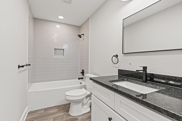 full bathroom featuring tiled shower / bath, toilet, vanity with extensive cabinet space, and wood-type flooring