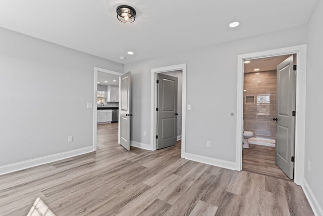 unfurnished bedroom featuring connected bathroom and light wood-type flooring