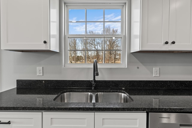 kitchen with dark stone countertops, sink, white cabinetry, and a wealth of natural light