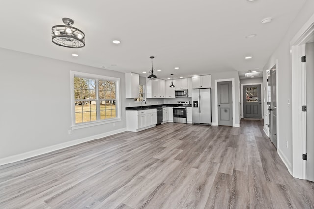 kitchen with decorative light fixtures, light hardwood / wood-style floors, white cabinets, stainless steel appliances, and sink