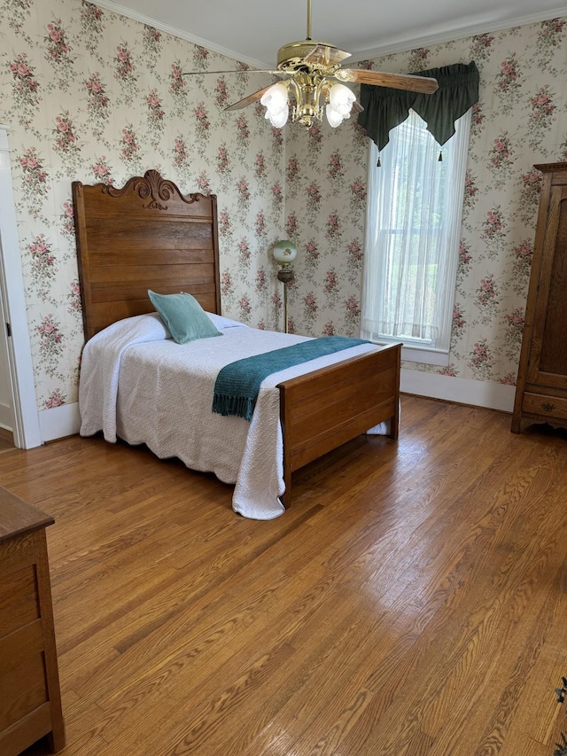 bedroom featuring hardwood / wood-style floors, ceiling fan, and ornamental molding