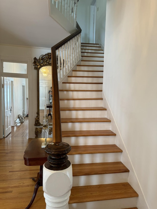 staircase featuring wood-type flooring and ornamental molding