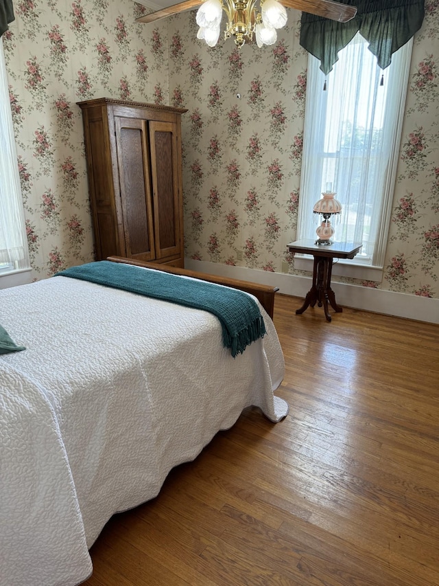 bedroom featuring hardwood / wood-style flooring and ceiling fan with notable chandelier