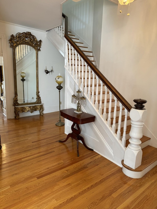 stairs with hardwood / wood-style flooring and ornamental molding