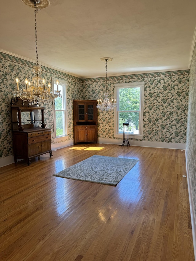 unfurnished living room with a chandelier, wood-type flooring, and ornamental molding