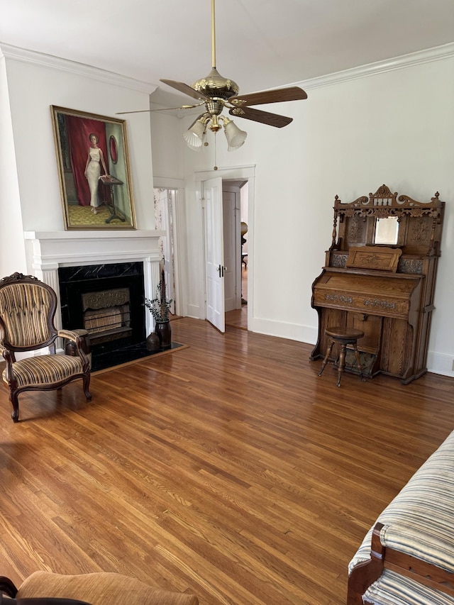 sitting room with ceiling fan, a fireplace, dark hardwood / wood-style floors, and ornamental molding