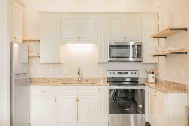 kitchen featuring white cabinets, appliances with stainless steel finishes, sink, and light stone countertops