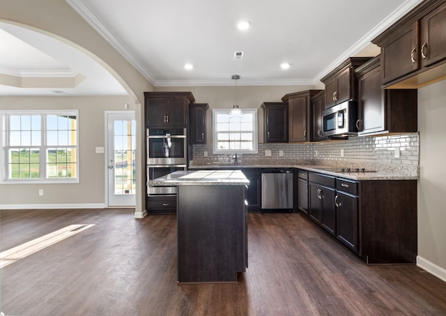 kitchen featuring a center island, light stone counters, dark hardwood / wood-style flooring, pendant lighting, and appliances with stainless steel finishes