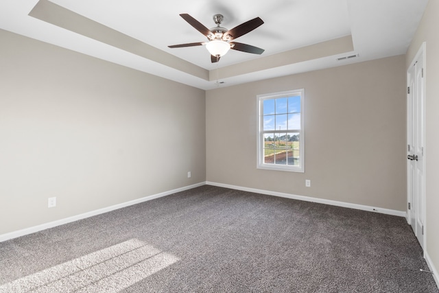 carpeted empty room with ceiling fan and a raised ceiling