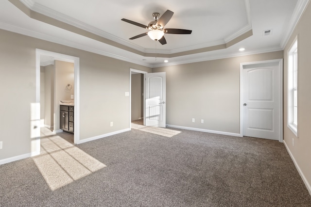 unfurnished bedroom featuring ensuite bath, ceiling fan, ornamental molding, and a tray ceiling