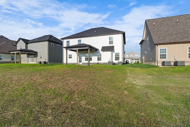 rear view of house featuring central AC unit and a lawn