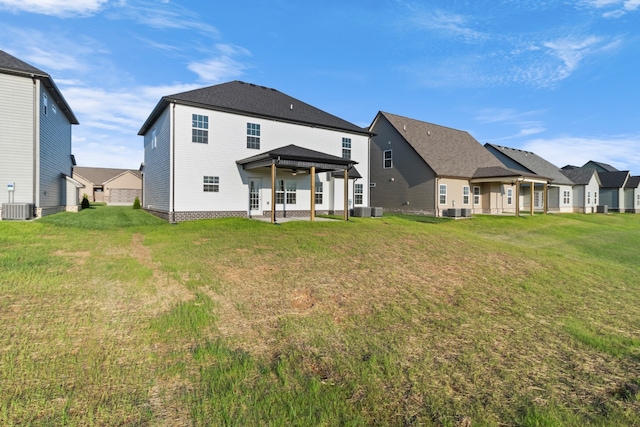 rear view of house with a lawn, central AC, and a gazebo