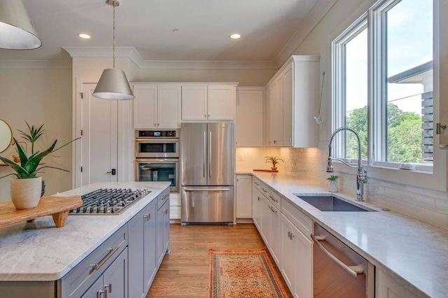 kitchen featuring stainless steel appliances, white cabinets, backsplash, hanging light fixtures, and light wood-type flooring