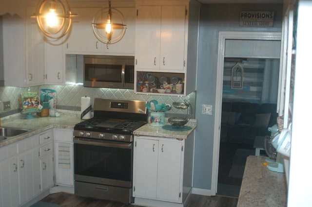 kitchen featuring backsplash, white cabinets, pendant lighting, and appliances with stainless steel finishes