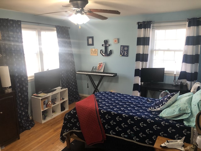 bedroom with ceiling fan, wood-type flooring, and multiple windows