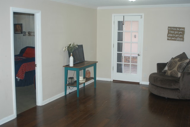 sitting room with ornamental molding and dark wood-type flooring