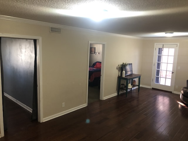 interior space with a textured ceiling, crown molding, and dark hardwood / wood-style floors