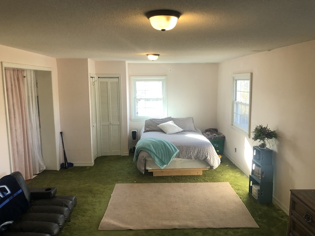 bedroom with two closets, a textured ceiling, and dark colored carpet