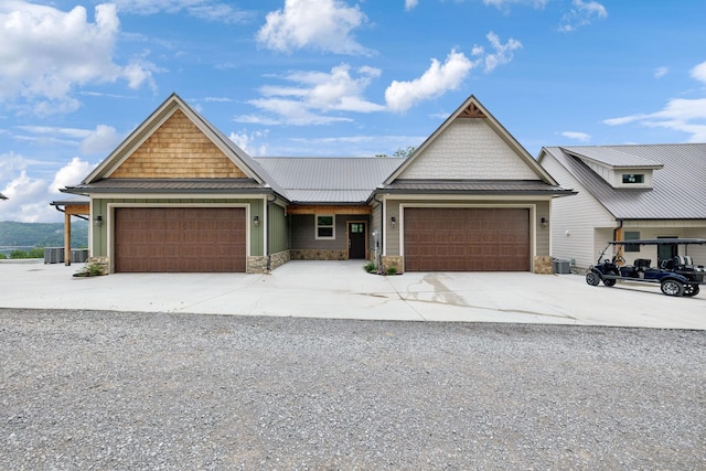 craftsman-style home featuring an attached garage, a standing seam roof, central AC, metal roof, and stone siding