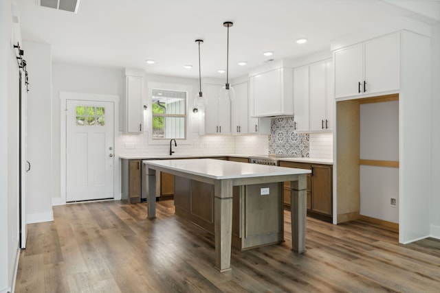 kitchen featuring pendant lighting, backsplash, a center island, white cabinets, and dark wood-type flooring