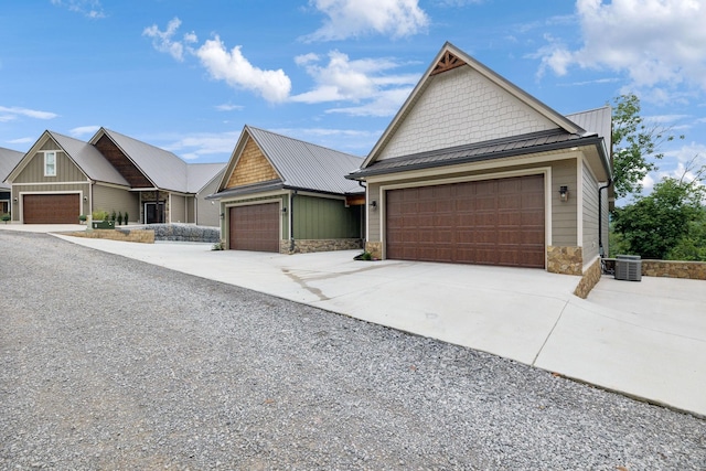 craftsman-style house with a standing seam roof, central AC, metal roof, stone siding, and driveway