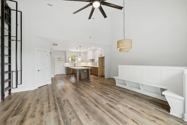 living room featuring light hardwood / wood-style flooring, sink, ceiling fan, and a high ceiling