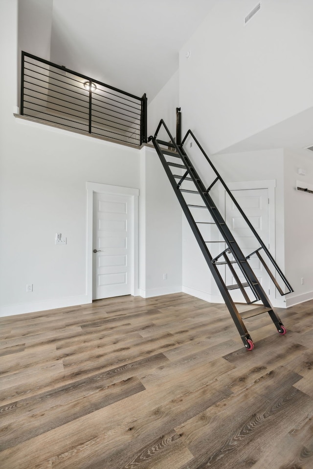 stairs with hardwood / wood-style floors and a high ceiling