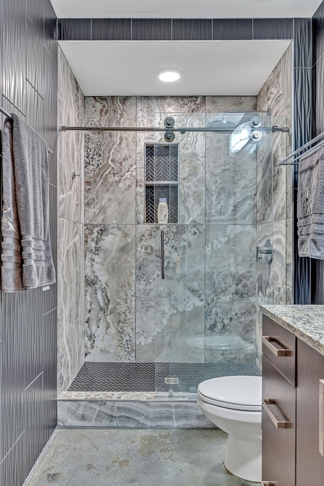 bathroom with tile walls, toilet, vanity, and a shower with door