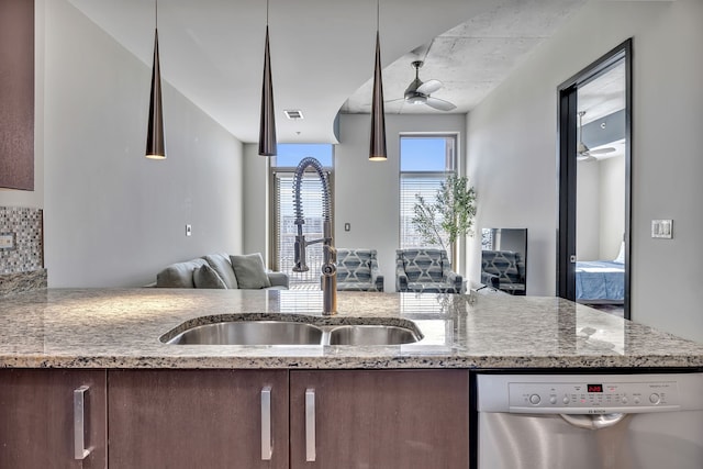 kitchen with pendant lighting, ceiling fan, light stone counters, dishwasher, and sink