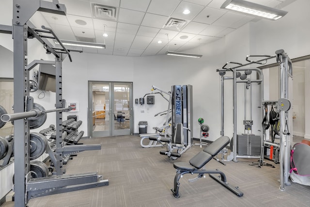 workout area featuring french doors, a drop ceiling, and light carpet