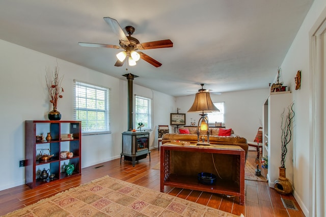 interior space featuring ceiling fan, a wood stove, and hardwood / wood-style floors