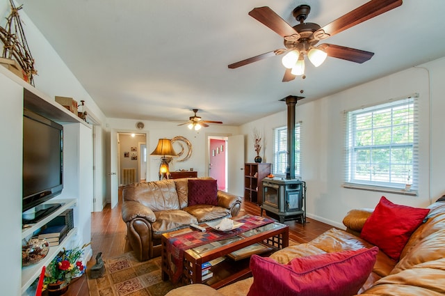 living room featuring dark hardwood / wood-style flooring, ceiling fan, and a wood stove