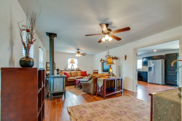 living room featuring ceiling fan, a wood stove, and light wood-type flooring