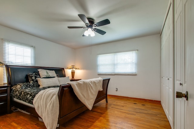 bedroom with multiple windows, light wood-type flooring, ceiling fan, and a closet