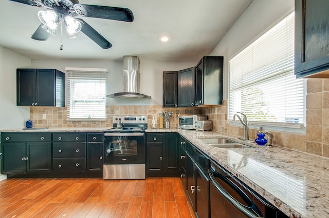 kitchen featuring stainless steel appliances, wall chimney range hood, tasteful backsplash, light hardwood / wood-style flooring, and sink