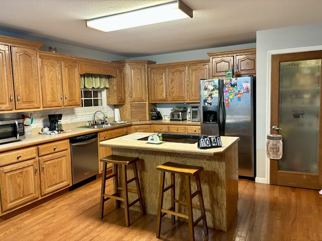 kitchen with a center island, a kitchen breakfast bar, stainless steel appliances, and light wood-type flooring