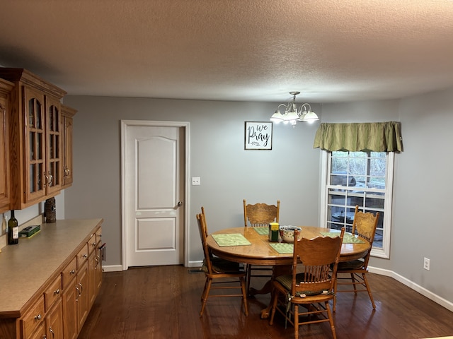 dining area featuring an inviting chandelier, dark hardwood / wood-style floors, and a textured ceiling