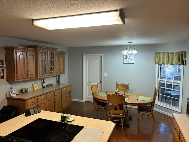 kitchen with a textured ceiling, a notable chandelier, hanging light fixtures, and dark wood-type flooring