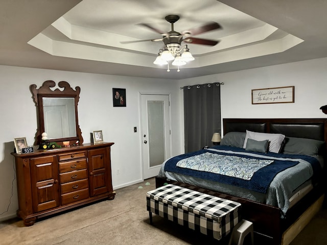 carpeted bedroom with ceiling fan and a tray ceiling