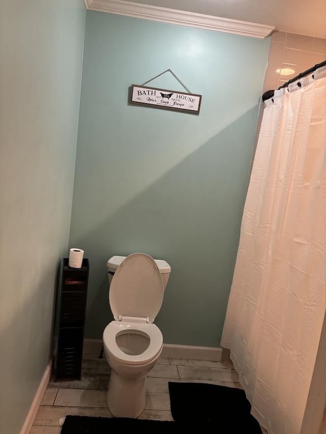 bathroom with ornamental molding, toilet, and tile flooring