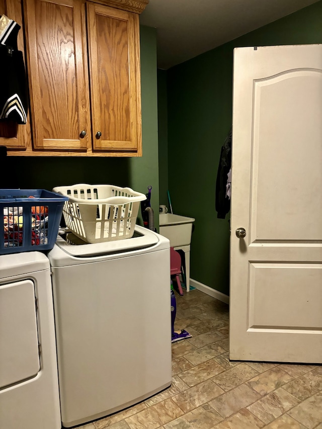 washroom with washing machine and dryer, cabinets, and light tile floors