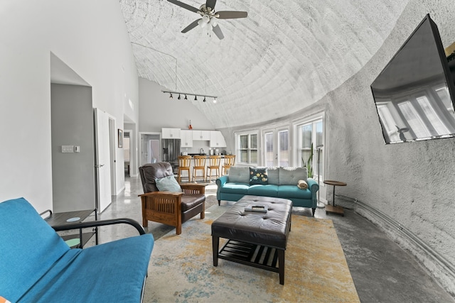 living room with ceiling fan, a textured ceiling, concrete flooring, and rail lighting