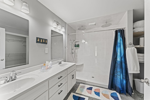 bathroom featuring tiled shower and double sink vanity