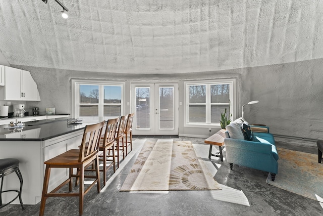 kitchen with french doors, a breakfast bar area, a textured ceiling, and white cabinets