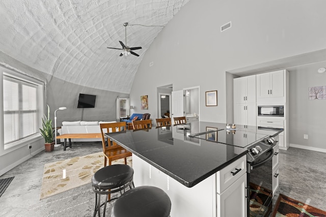 kitchen featuring a kitchen breakfast bar, ceiling fan, black appliances, and white cabinetry