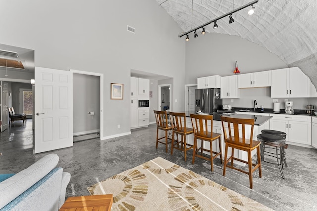 dining room with a textured ceiling, a high ceiling, sink, and track lighting