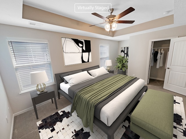 carpeted bedroom featuring a closet, ceiling fan, and a raised ceiling